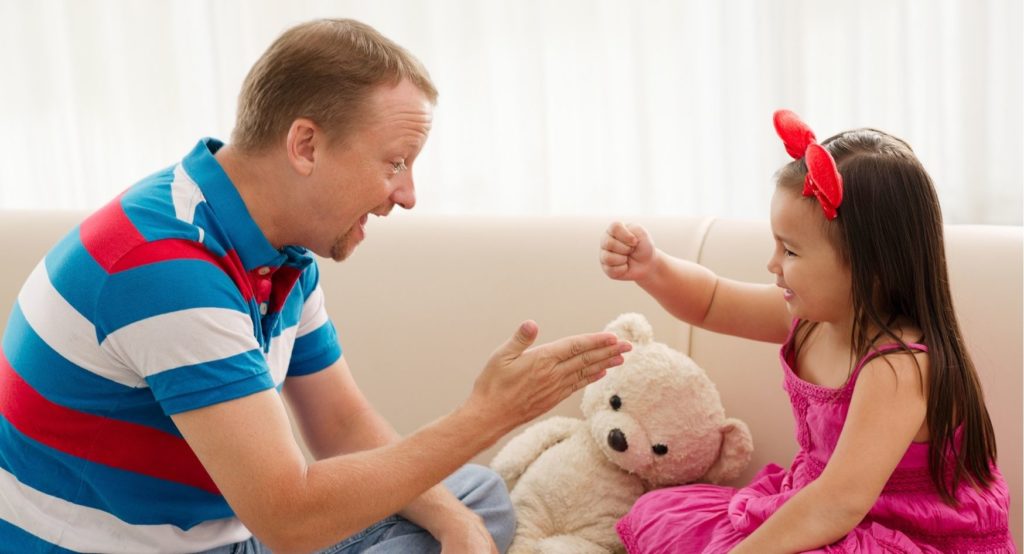 Father playing with daughter on sofa