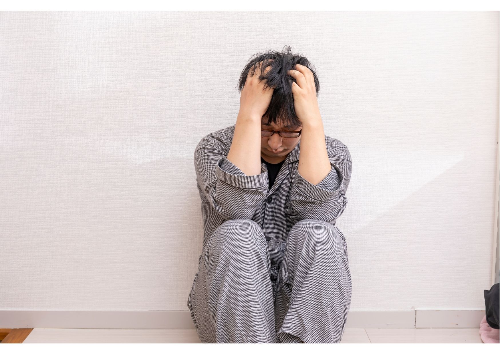 Man sitting on floor holding head in his hands