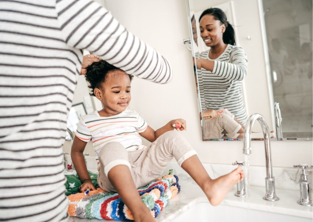 Boy sitting on bathroom counter with foot under tap